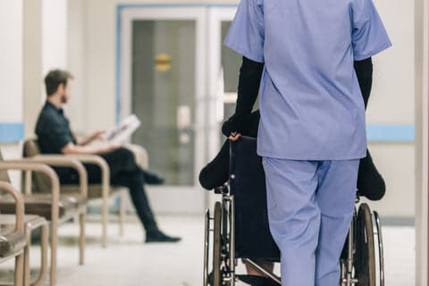 Pflegekraft schiebt Rollstuhl